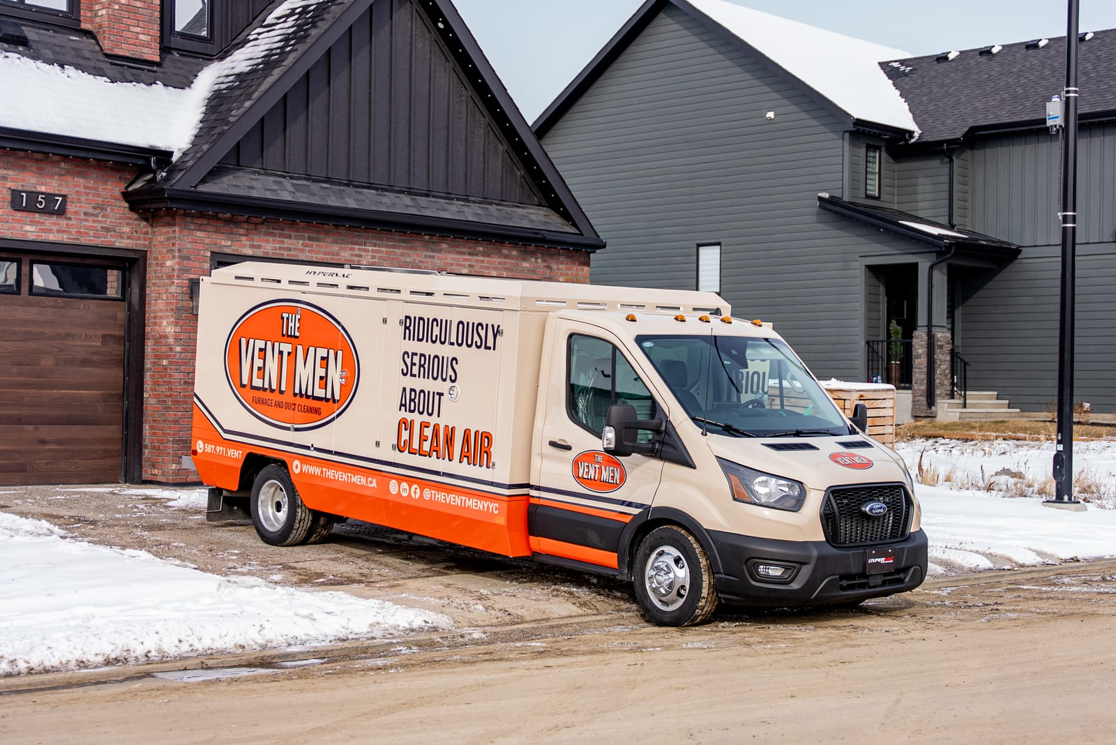 The Vent Men wrapped Ford Transit T350 parked in front of a modern navy Calgary home, snow on ground, side panel reading Ridiculously Serious About Clean Air